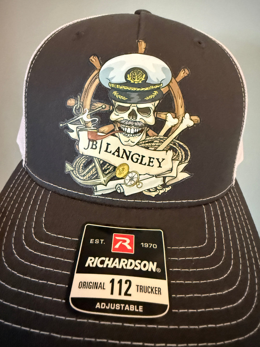 Black cap with a skull and crossbones design and Richardson label on a light gray background